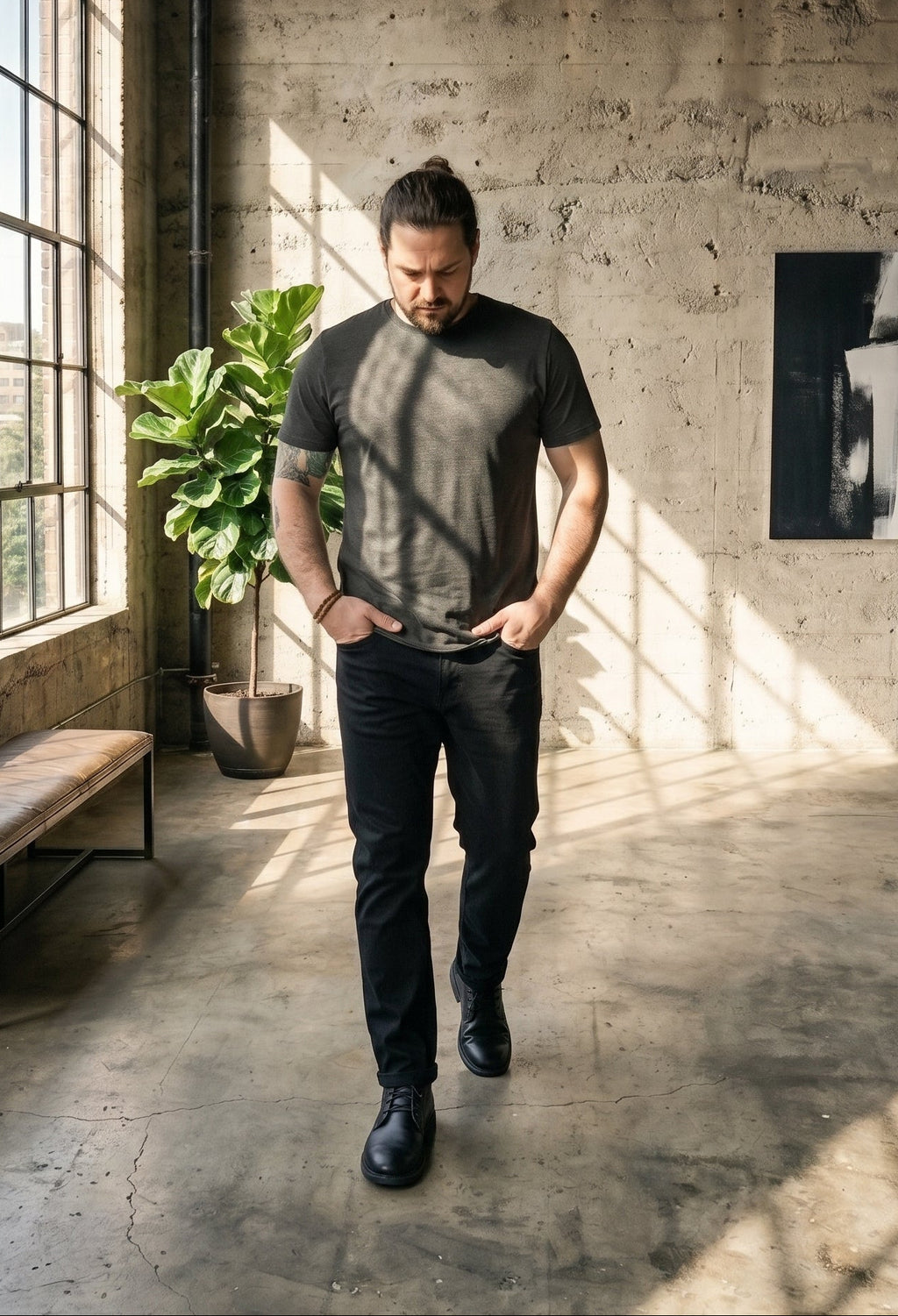 Man walking in a sunlit room with large windows and concrete walls.